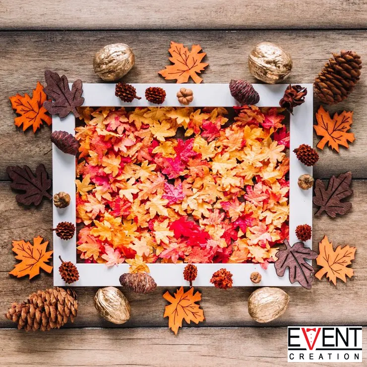 A flat lay of a square white picture frame filled with a dense, colorful mix of faux maple leaves.