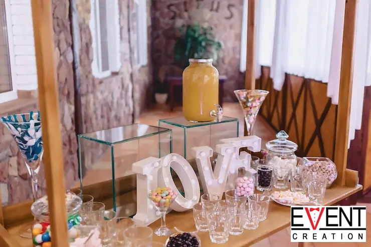 A colorful candy and dessert bar setup on a rustic wooden cart at a wedding reception.