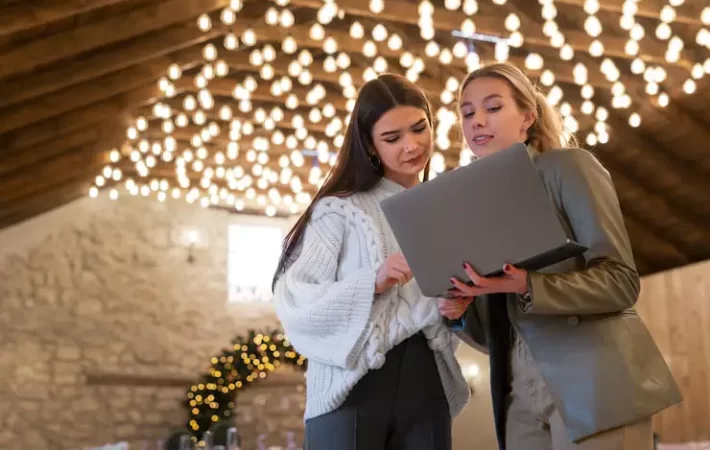 Event planners using laptop at a decorated venue space.